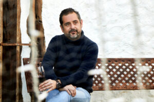 Iván Sanz sentado con una copa de vino en un entorno rústico.