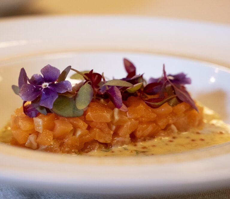 Plato gourmet con flores comestibles y salsa en un restaurante