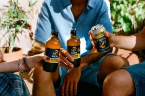 Botellas y latas de El Águila Sin Filtrar Limón en manos de personas