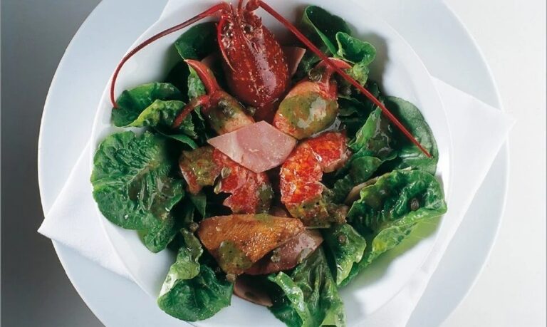 Ensalada de bogavante con lechuga y aderezo en un plato blanco.