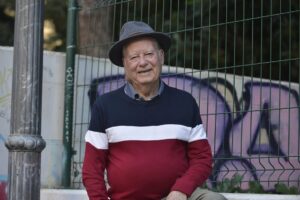 Hombre mayor con sombrero sonriendo en un entorno urbano