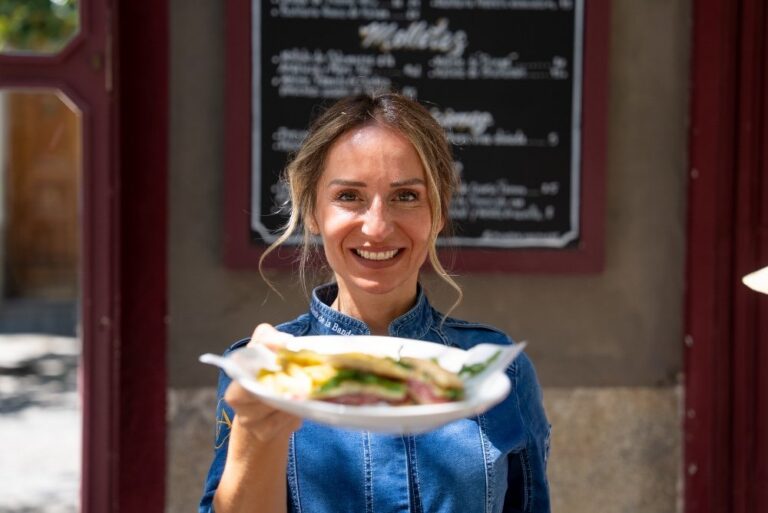 Mujer sonriente sosteniendo un mollete en Casa Orellana, Madrid.