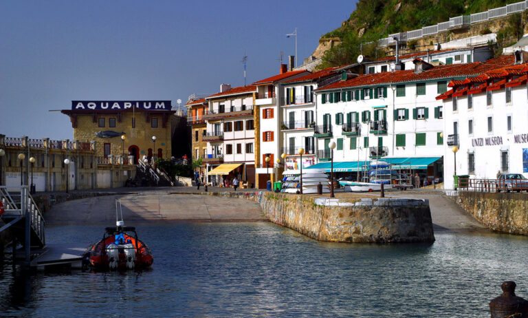 Vista del puerto de Hondarribia con edificios coloridos y un bote en el agua.