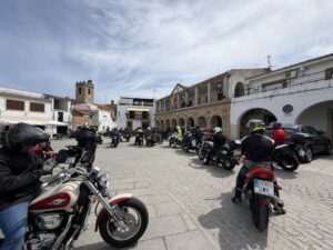 Participantes en la ruta motera en una plaza con motos aparcadas