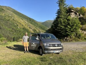 Hombre junto a un vehículo en el Valle del Oja rodeado de montañas