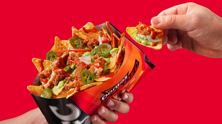 Tiras de pollo frito sobre nachos Doritos con guacamole y jalapeños