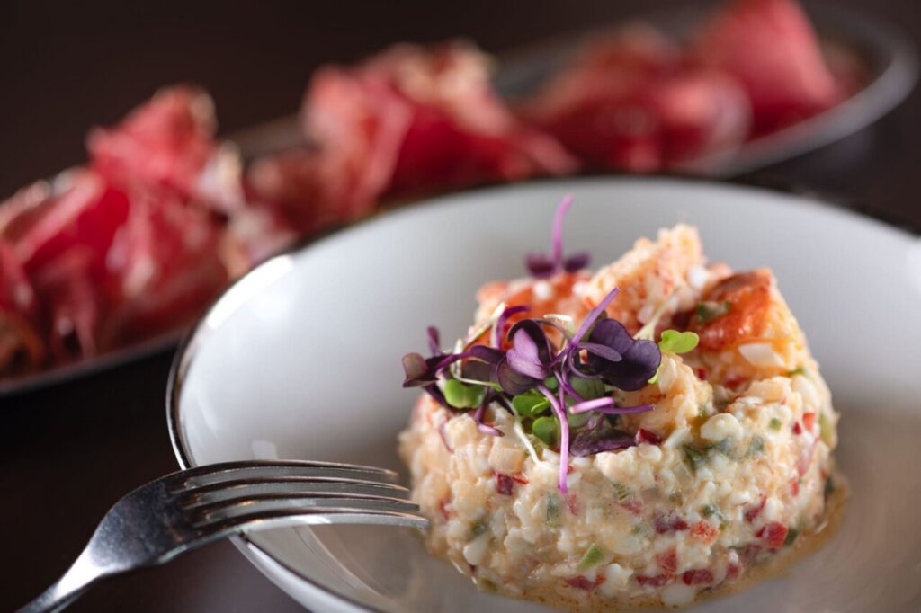 Salpicón con ingredientes frescos y decoración de hierbas en plato blanco