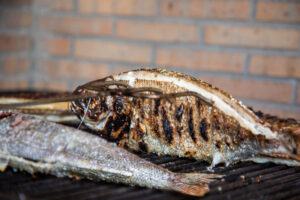 Pescado asado sobre parrilla con fondo de ladrillos