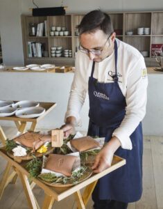 Cocinero preparando platos en El Coto de Quevedo con ingredientes frescos.