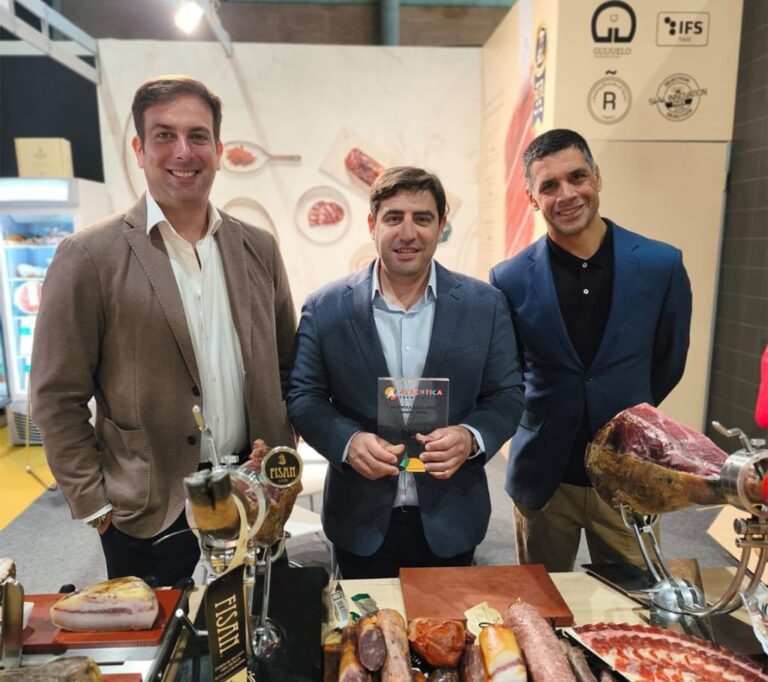 Tres hombres sonrientes sosteniendo un premio en un evento de productos ibéricos.