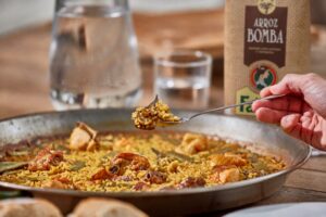 Plato de paella con mariscos y pollo servido en una mesa