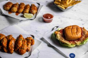 Plato de pollo crujiente y alitas con salsas en un restaurante