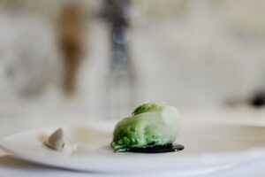 Cogollo verde presentado sobre un plato blanco con una salsa oscura.