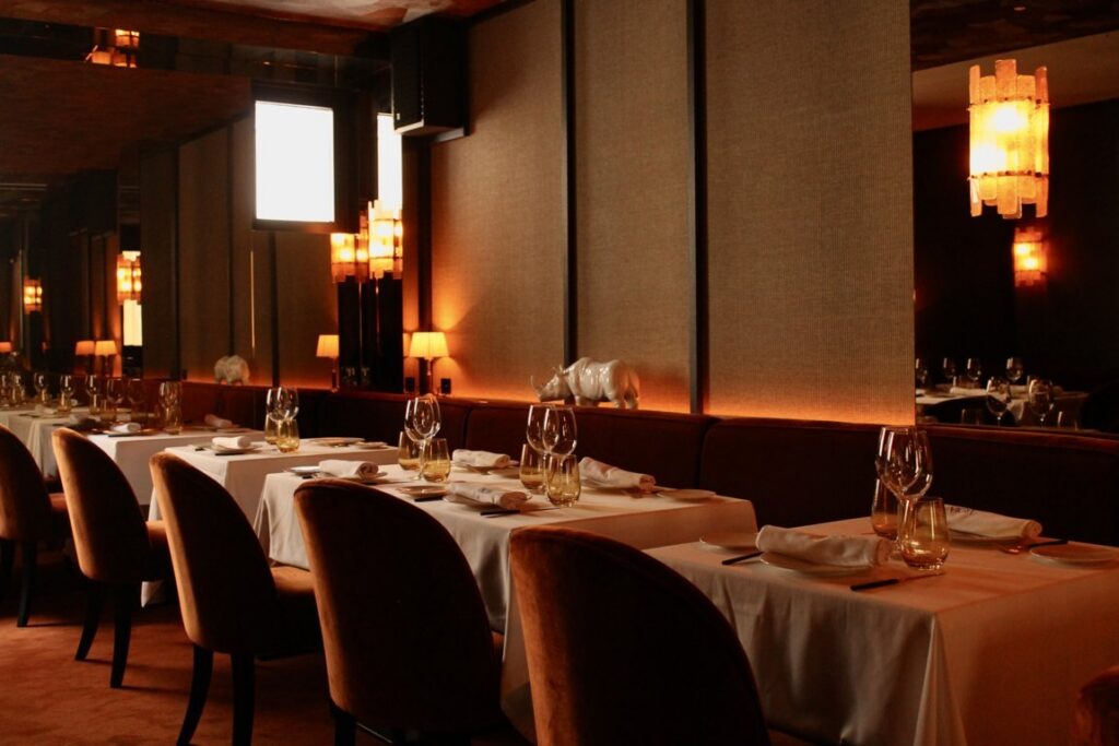 Comedor de restaurante con mesas vestidas, copas y lámparas de luz cálida