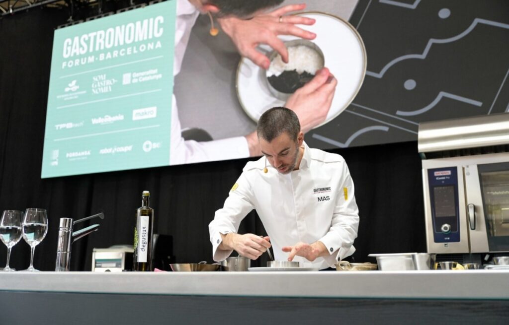 Una persona con chaqueta blanca prepara un plato en un mostrador del Gastronomic Forum Barcelona
