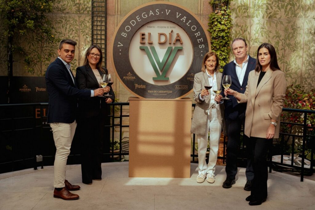 Cinco personas posan junto al emblema de El Día V y sostienen copas de vino.