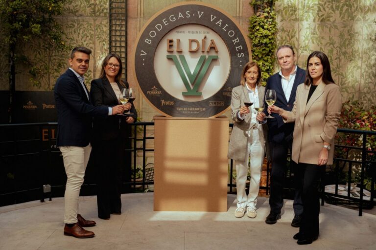 Cinco personas posan junto al emblema de El Día V y sostienen copas de vino.