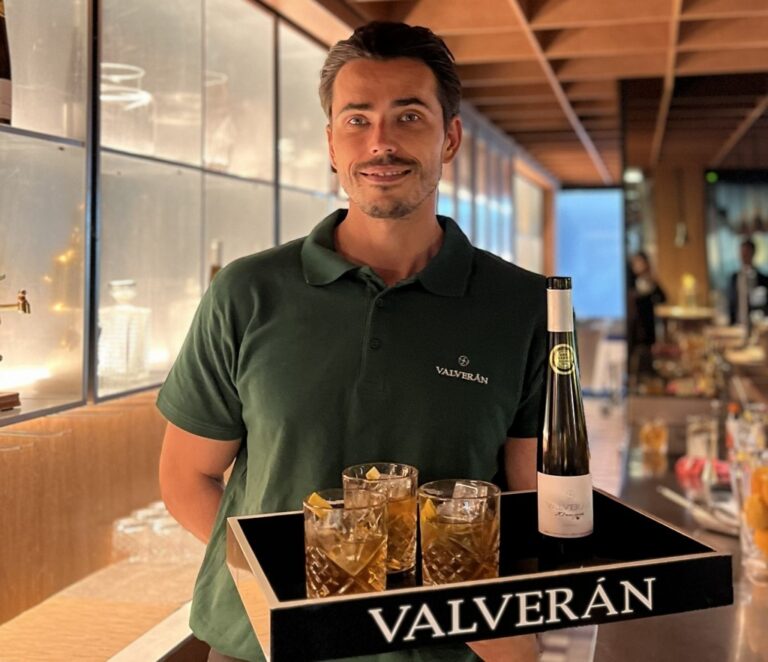 Un hombre sostiene una bandeja con tres vasos de cóctel y una botella Valverán.