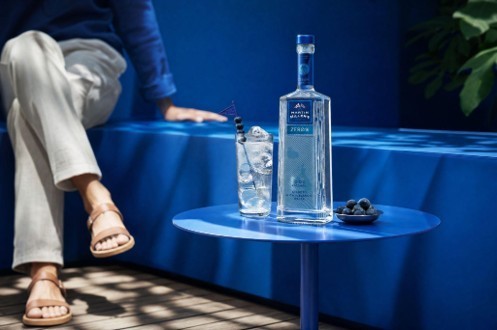 Botella de Martin Miller’s sobre una mesa azul junto a un vaso con hielo.