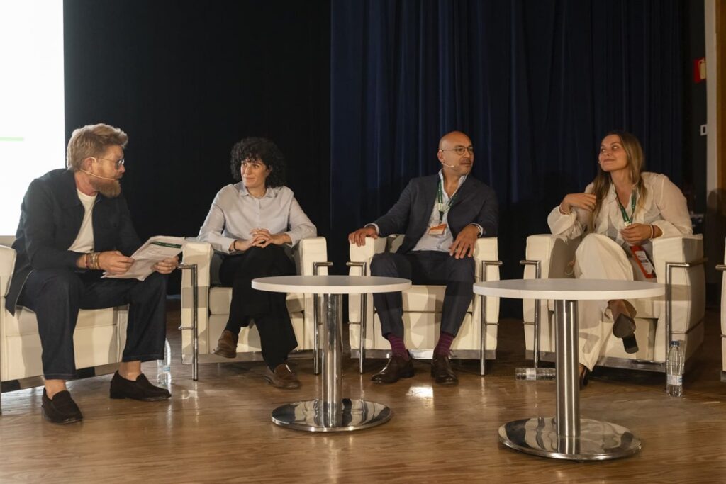 Cuatro personas participan en una mesa de diálogo sentadas en un escenario.