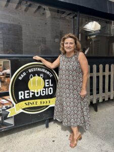 Una mujer posa junto al rótulo del bar-restaurante El Refugio.