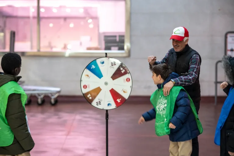 Un hombre y varios niños con delantales verdes participan junto a una ruleta.