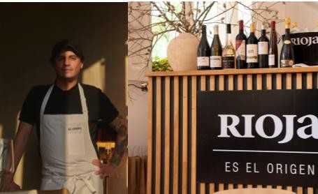 Una persona con delantal aparece junto a botellas y un expositor de Rioja.