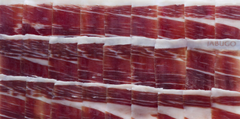Lonchas de jamón ibérico de Jabugo dispuestas en una tabla.