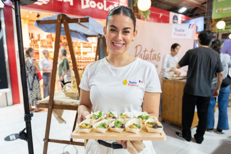 Mujer sonriente sosteniendo una bandeja con degustaciones de patatas francesas