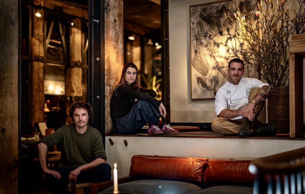 Tres personas posan sentadas en distintos niveles dentro de un restaurante.
